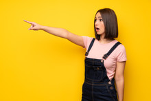 Young Woman Over Yellow Wall Pointing Away