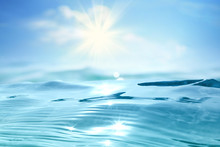 Abstract Summer  Landscape, Nature Of Tropical With Beautiful Sun Glare On Wave Sea Water Close-up,  Blurred Blue Sky With Rays Of Sunlight And White Clouds. Copy Space, Summer Vacation Concept.