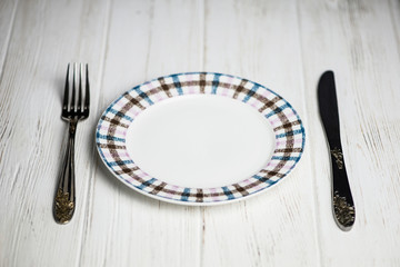 Wall Mural - clean plate, fork and knife on wooden background