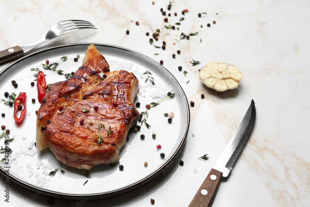 Plate with tasty cooked meat and spices on light background