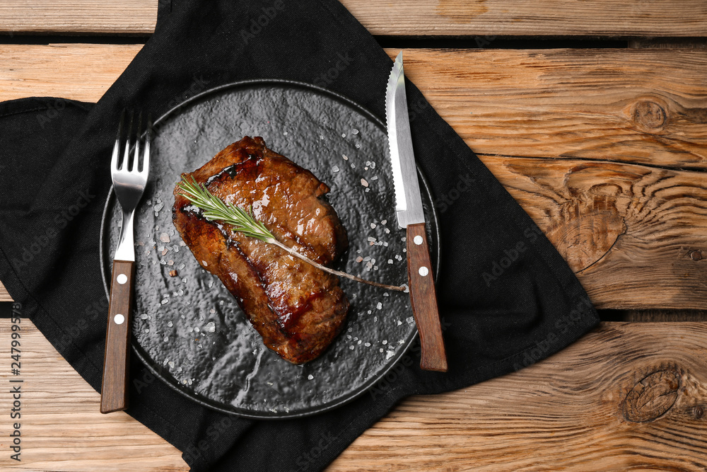 Plate with tasty cooked meat on wooden background
