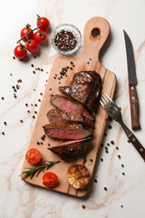 Board with tasty cooked meat and spices on light table