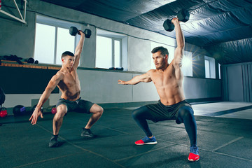 Wall Mural - Athletic man doing exercise for arms. Photo of muscular fitness male athletes working out with dumbbells at gym. Healthy lifestyle concept