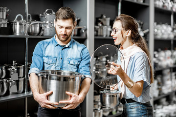 Couple choosing pans for cooking in the shop