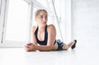 © Rithor - Young beautiful girl athlete in a tracksuit resting lying on a white podium in the gym. Sport training concept