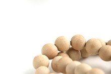 String Of Unvarnished Wooden Beads On A White Surface, Shot With A Short Depth Of Field