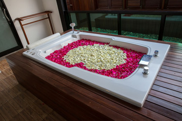 A relaxing bath with rose. bath tub with floating petals. Rose petals put in bathtub for romantic bathroom in honeymoon suit. Arranged by interior designer for honeymoon couple.