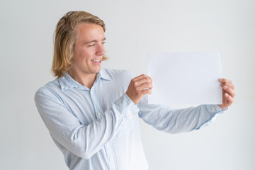 Wall Mural - Happy young man showing blank sheet of paper