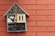 Insect and butterfly hotel on a red brck wall with copy space to the right, can be used for new home greeting card