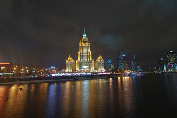 Wall Mural - Hotel Ukraine (Radisson Royal Hotel) in bright lights and Moskva river in night winter reflections of the night Moscow.. MIBC (Moscow International Business Center) as background.