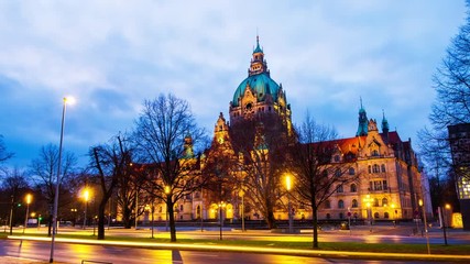 Wall Mural - Hanover, Germany. The New Town Hall in Hanover, Germany at sunrise. Time-lapse of the road and illuminated landmark with cloudy sky in the morning, zoom in