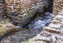 The Water Flows Through A Channel That Is Laid Out Of Stones; Both Sides Have Decorative Walls Made Of Stones