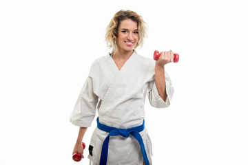 Wall Mural - Portrait of female wearing martial arts costume training with dumbbells