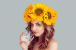 © hbrh - Face portrait of woman in floral crown from sunflowers drinking water. Smiling girl looking at camera holding a glass of water isolated on gray background