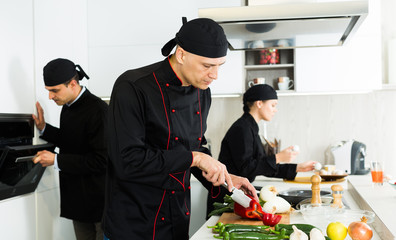 Wall Mural - Male cook is making salad on his work place in the kitchen