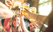 Friends drinking and toasting beer at brewery bar restaurant - Friendship concept on young millenial people having fun together on happy hour at brew pub - Focus on girl face - Summer sunshine filter