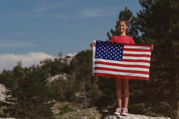 Child teenager girl holding an American flag at nature background. USA 	 resident, US citizen. Immigration concept