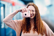 Positive redhead young female with pink photo snap instant digital camera with printer.