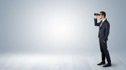 Wall Mural - businessman looking forward with binoculars in an empty space