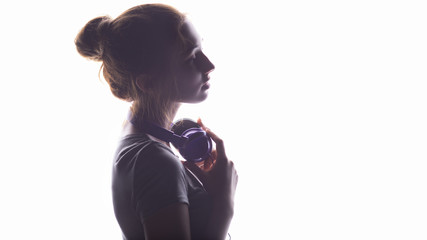 Wall Mural - silhouette of a romantic girl listening to music in headphones, young woman relaxing on a white isolated background, concept of hobby and leisure