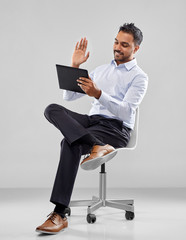 Sticker - business, technology and people concept - smiling indian businessman having video call ob tablet computer sitting on office chair over grey background