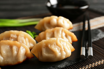 Tasty Japanese gyoza on slate plate, closeup