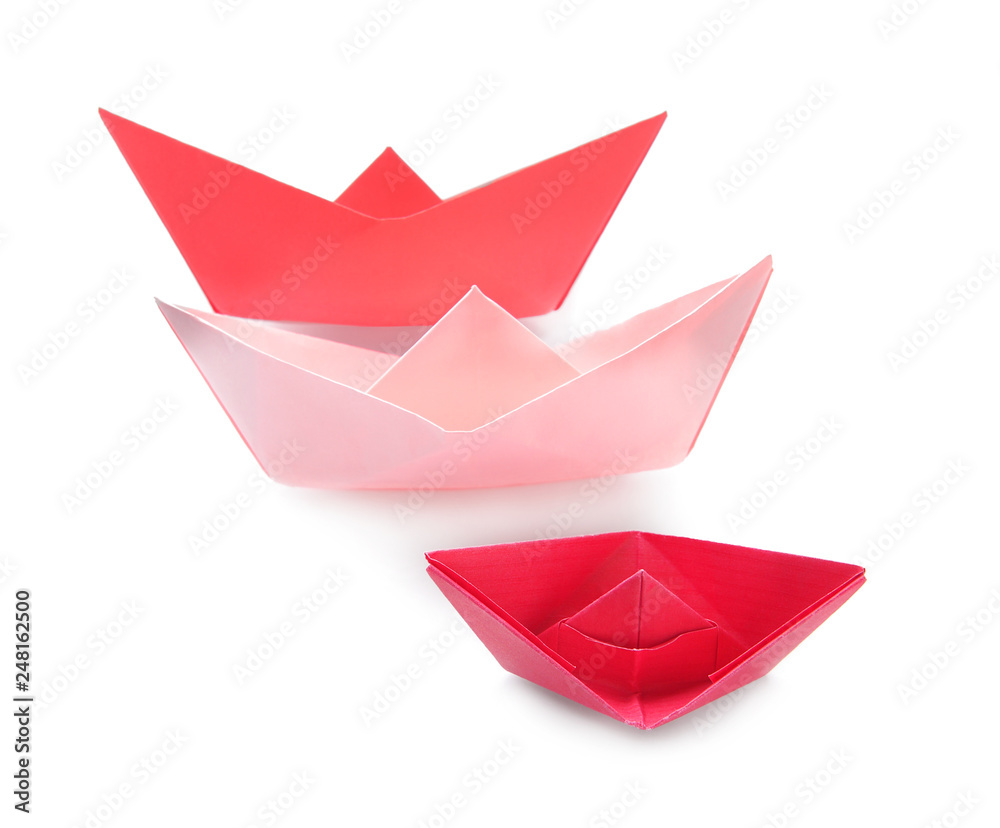 Red and coral origami boats on white background