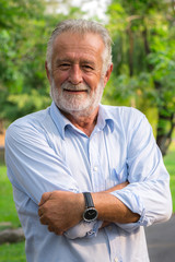 Portrait of happy senior man standing in the park. Elder health and retirement concept.