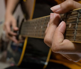 Fototapeta Desenie - Woman's hands playing acoustic guitar.