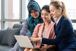 © InfiniteFlow - Multicultural working group. Team of businesswomen of different ethnicity, Caucasian, Asian and Arabic working together with laptop computer at office workplace. Multiethnic teamwork concept.