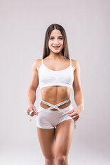 Wall Mural - Fitness young woman taking body measurements with tape isolated over a white background