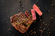Restaurant cooking art. Grilled steak sliced on textured black background.