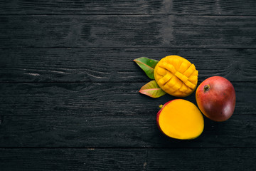 Mango with leaves on a black wooden background. Tropical Fruits. Top view. free space for your text.