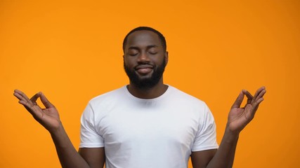 Wall Mural - Pacified black man meditating against yellow background, breathing exercises