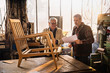 Two craftsmen in their workshop working on an armchair frame