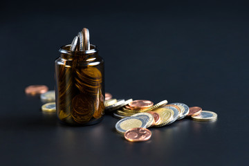 Coins in a glass bottle on a black background.