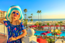 Summer Holidays In California. Happy Lifestyle Tourist Woman In Hat Enjoying In Coronado Island, San Diego. Aerial View Of Swimming Pool And Palm Trees Of Beachfront Luxury Hotel. Sunset Light.