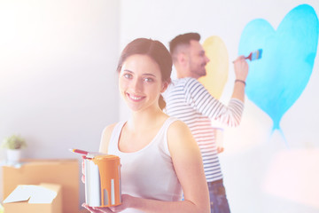 Wall Mural - Portrait of happy smiling young couple painting interior wall of new house. young couple