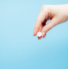 Wall Mural - Close-up shot of pill in nurse's hand isolated over blue background. Copy space