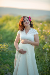 Wall Mural - Outdoor natural portrait of beautiful pregnant woman in white dress