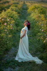 outdoor natural portrait of beautiful pregnant woman in white dress