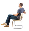 © ghoststone - Side view of a man sitting on a chair.