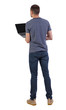 © ghoststone - Back view of a man who is standing with a laptop.