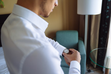 Wall Mural - Close-up man puts on a gold watch with a leather belt, businessman is dressed in a stylish suit, a white shirt.