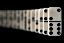 A Curved Row Of White Domino Game Stones Standing On A Black Background.