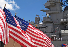 US Flags Flying Beside The Battleship Missouri In Pearl Harbor, Honolulu, Oahu, Hawaii With 4 Sailors Walking On Deck.