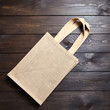 Reusable shopping bag, natural textile fiber, blank eco hessian or jute sack on brown wooden background