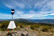 The trig station at the summit of Mt Richardson with a view of the surrounding mountains, New Zealand