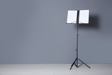 Sticker - Note stand with music sheets near grey wall indoors. Space for text