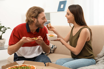 Wall Mural - Young couple having lunch in living room. Food delivery